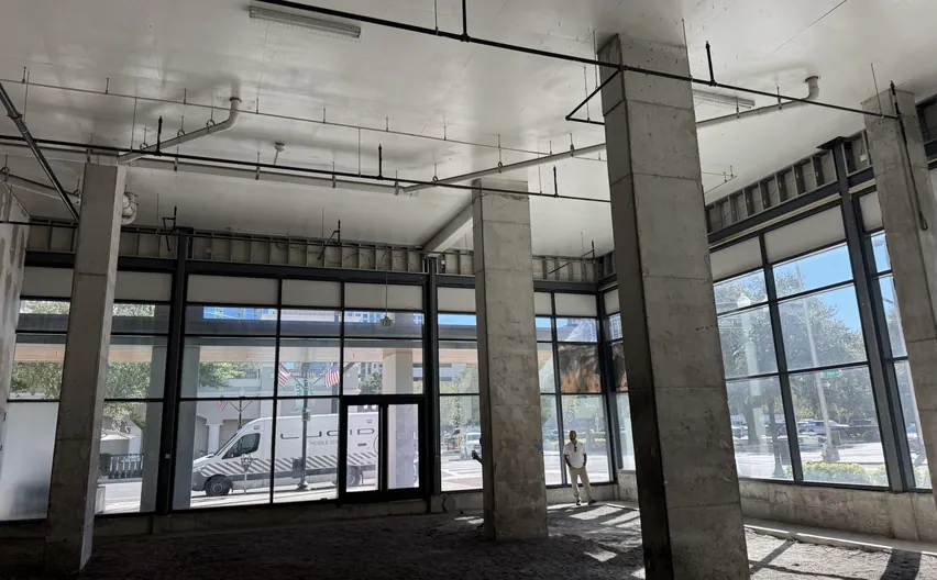 An empty commercial shell space with storefront glazing, columns and an open ceiling