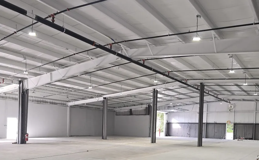 A large industrial interior with a high open-web joist ceiling, from an industrial addition and renovation
